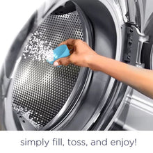 Hand adding Downy Ocean Mist scent booster beads into front-load washing machine drum for fresh laundry