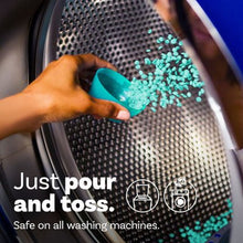Hand pouring blue Downy Unstopables scent booster beads into washing machine drum for fresh laundry